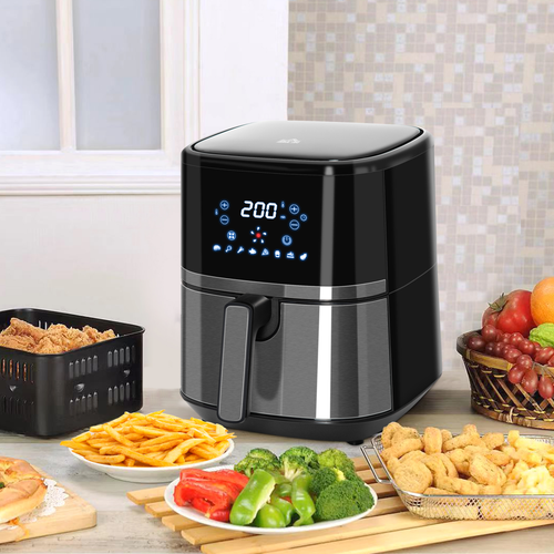 Black air fryer on a kitchen counter with various foods around it.