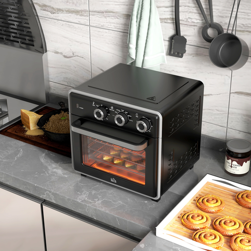 Black toaster oven on a kitchen counter with cinnamon rolls and a jar of jam.