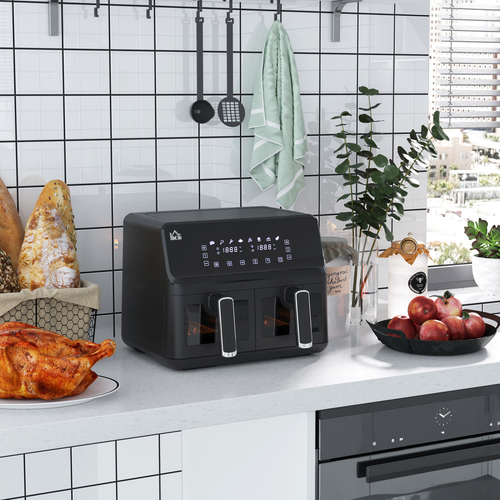 Black air fryer on a kitchen counter with a white tiled wall and various kitchen items.